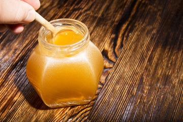jar of honey and spoon on a wooden background