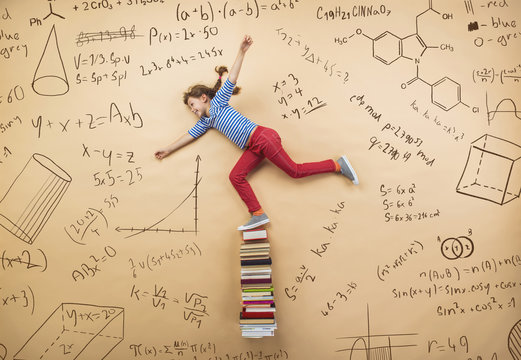 Cute girl learning playfully in frot of a big blackboard