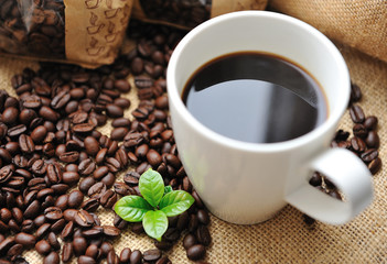 Cup of coffee with beans and leaf