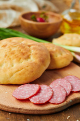 Sliced salami sausage and flat bread on a wooden board