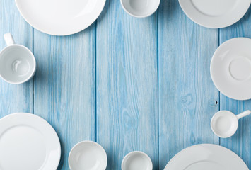 Empty plates and bowls on blue wooden background