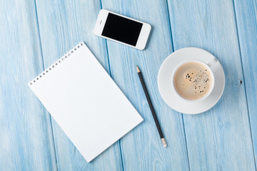 Coffee cup, smartphone and blank photo frame on wooden table bac
