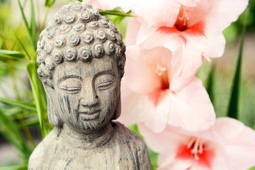 Grey buddha statue in flower garden with bamboo