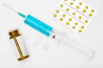 Pills and a syringe with blue liquid inside