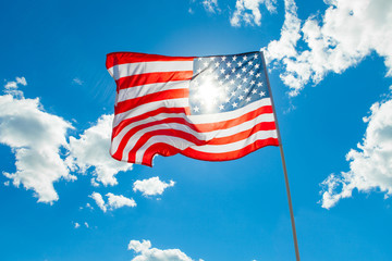 US flag with cumulus clouds and blue sky on background