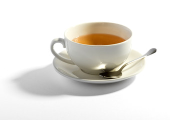Milky tea in a cup with a teaspoon