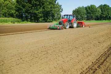 Obraz premium Ackerbau,Roter Schlepper mit schwerer Drillkombination beim Säen