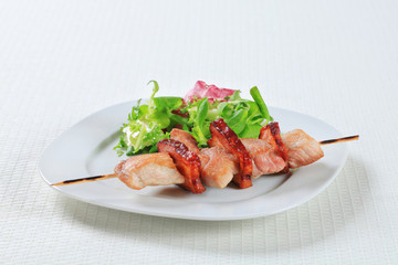 Pork skewer with salad greens
