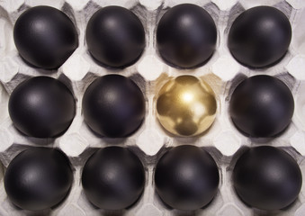 gold Easter egg between many black eggs