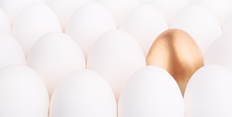 gold Easter egg between many white eggs