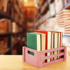 Books in wooden crate on bookshelves background