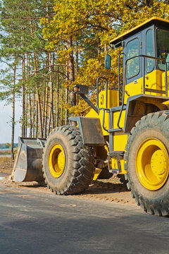 wheelloader in forest near edge of road rear view
