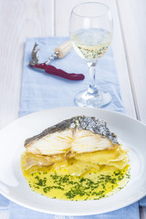 Bacalao asado con patatas y vino blanco para acompañar