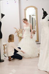 Beautiful young woman trying wedding dress in a bridal shop