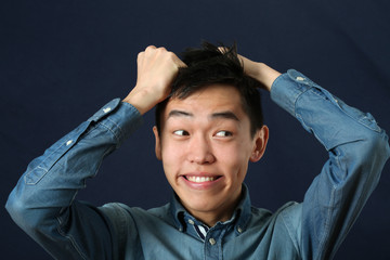 Funny young Asian man making face and looking sideways - obrazy, fototapety, plakaty