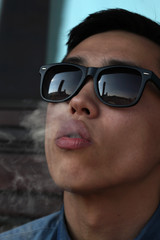 Handsome young Asian man smoking and looking upward