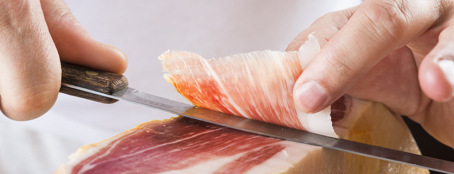 Profesional cortando lonchas de jam&oacute;n serrano a cuchillo