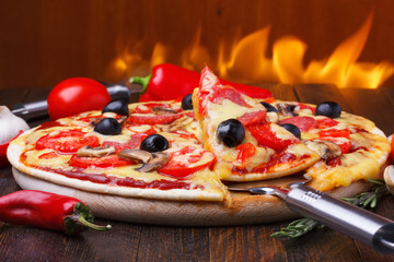 Pizza chaude cuite au four avec une tranche sur le poussoir avec le feu sur le fond