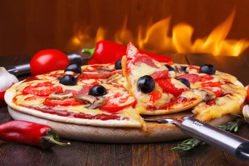 Papier Peint photo Lavable Pizzeria Pizza chaude cuite au four avec une tranche sur le poussoir avec le feu sur le fond