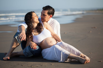 Mujer joven embarazada disfrutando de un hermoso día de sol con su esposo en la playa