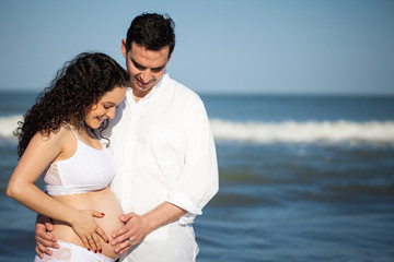 Mujer joven embarazada disfrutando de un hermoso día de sol con su esposo en la playa