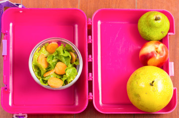 pink lunchbox with healthy food fruits and vegetables