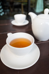 Fototapeta na wymiar White porcelain teacup and saucer with teapot