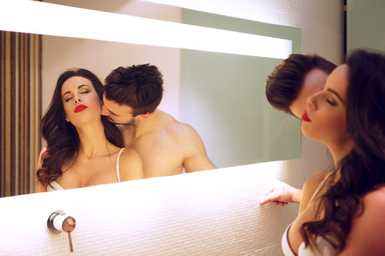 Sexy man kissing woman neck at mirror