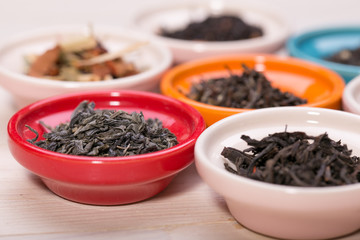assortment of dry tea in small bowl, on wooden background