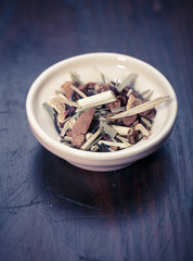 Bowl of dried green tea leaves on wooden background