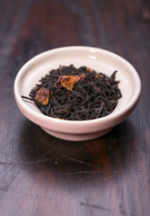 Bowl of dried green tea leaves on wooden background