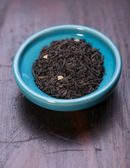 Bowl of dried green tea leaves on wooden background
