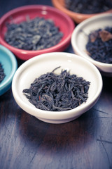 assortment of dry tea in small bowl, on wooden background