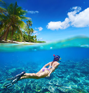 Woman floating underwater on background of islands, coral reef