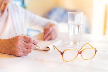 Hands of unrecognizable senior woman writing 