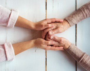 Unrecognizable grandmother and granddaughter holding hands