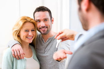 Real estate agent delivers keys of new house to young couple