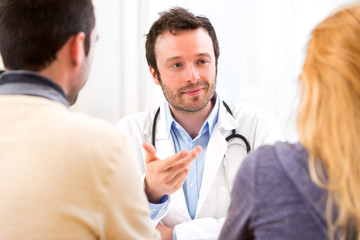 Young attractive doctor advising a young couple of patients