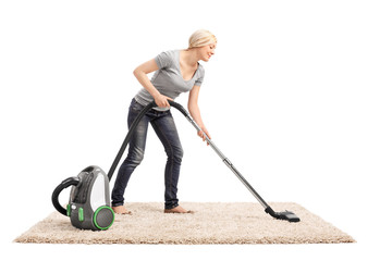 Woman vacuuming a carpet with vacuum cleaner