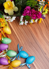 Easter flower arrangement and colorful eggs on wooden surface