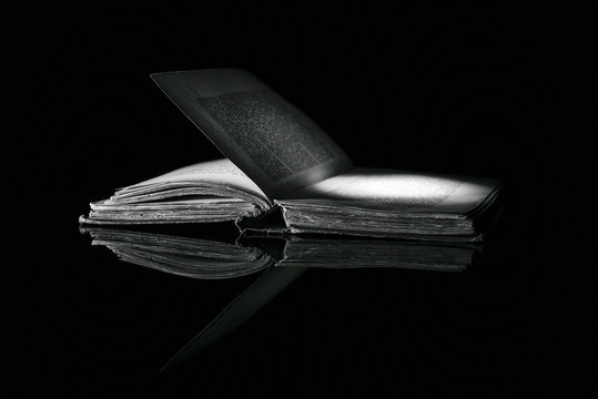 High contrast b&w old book on black reflective surface