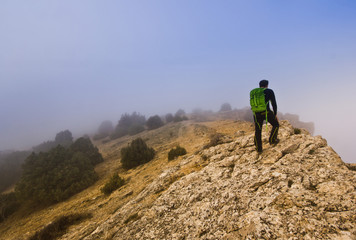 Obraz premium man walking on the edge of a cliff in foggy weather