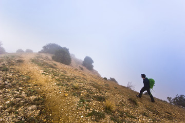 man walking on the edge of a cliff in foggy weather