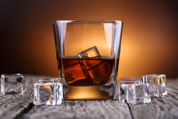 Glass of whiskey and ice on a wooden table.