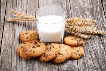Tasty cookies with milk on a wooden table.