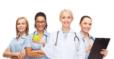Fototapeta premium smiling female doctor and nurses with green apple