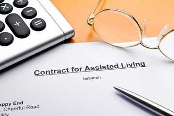 Contract for Assisted Living Facilities with calculator, reading glasses and ballpoint pen or biro.