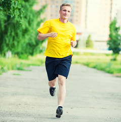 Sporty man jogging in city street park. Outdoor fitness.