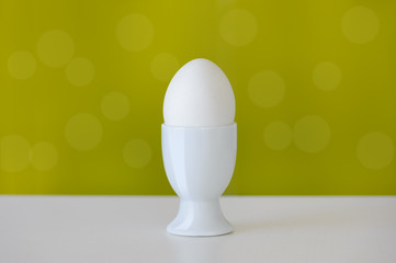 One egg in the eggcup on the green background