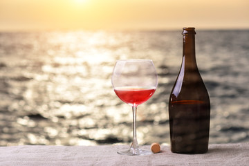 Bottle and glass of red wine on table against the sea ocean